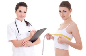 Female doctor and female patient measuring breast circumference