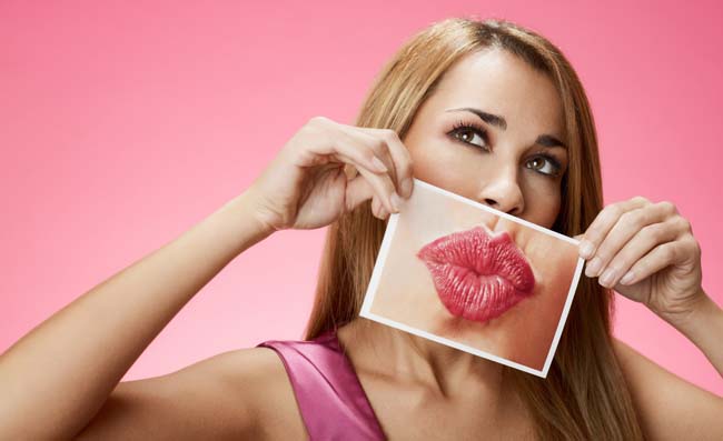 Woman holding a picture of her lips in front of her mouth
