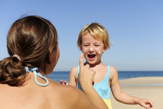Mom putting sunscreen on a young child