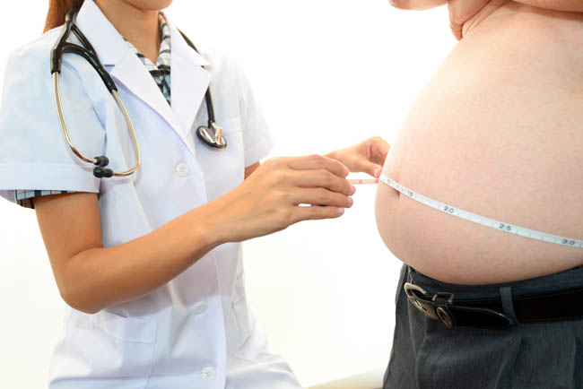 obese male patient getting midsection measured by physician