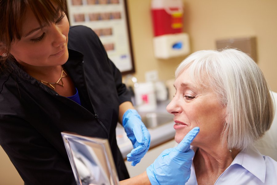 Nurse practitioners giving female patient a facial consult