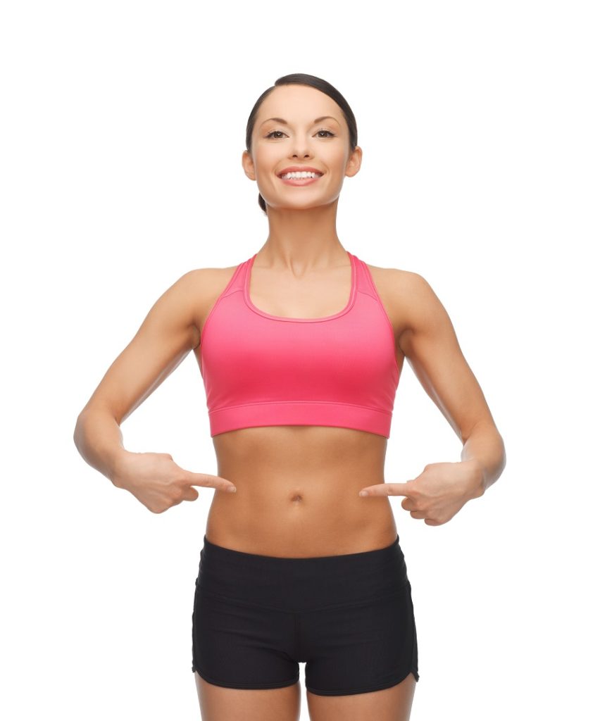 Fit female in exercise clothing pointing at her abs