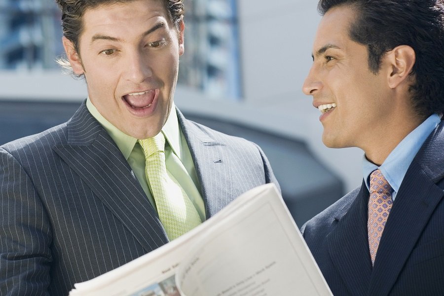 Two men in business suits looking at a book