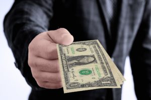 Male holding out dollar bills in his hand