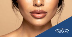 Close-up of a woman's glossy peach lips and chin against a beige background, with a blue diagonal banner showing the TAPAM logo in the bottom-right corner.
